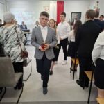 Uczniowie niosą kwiaty i znicze