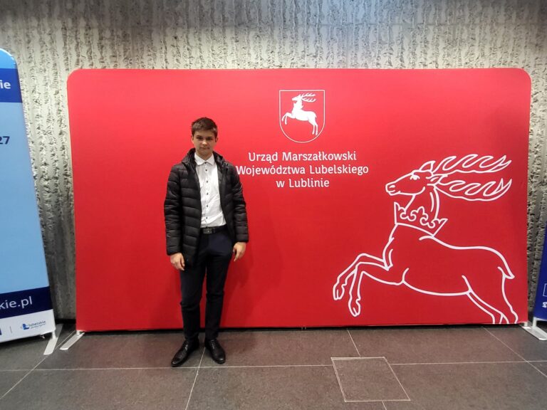 Uczeń ZSCKR na tle planszy Urzędu Marszałkowskiego