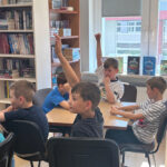 Uczniowie Szkoły Podstawowej zgłaszają się do odpowiedzi podczas zajęć